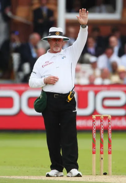 The umpire pulls one hand in the air.